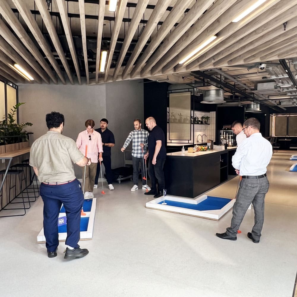 Colleagues Playing Crazy Golf - Workplace Putt-Off Event Colleagues playing crazy golf together during a work event