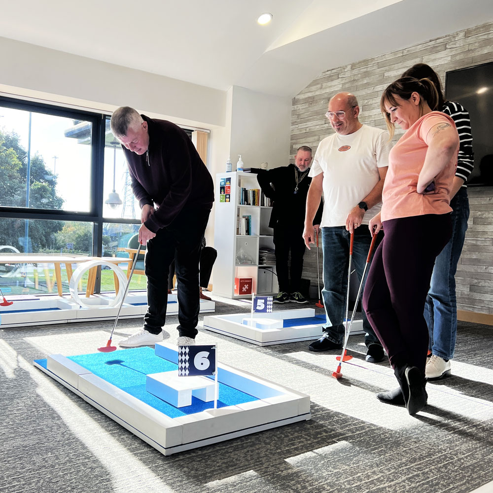 Indoor Mini Golf Course - Workplace Putt-Off Event Workplace team enjoying a portable mini golf course indoors